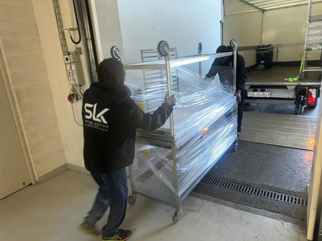 Chargement professionnel — chariot métallique sous film étirable, monté sur rampe vers le camion