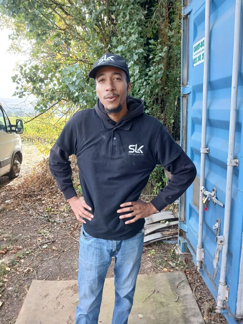 Membre de l'équipe SENLINK souriant, en sweat SLK