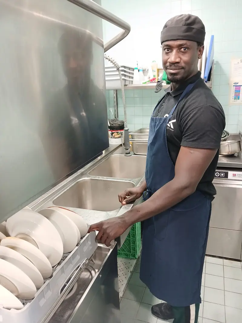 Plongeur SENLINK souriant au poste de plonge d'une cuisine de restaurant