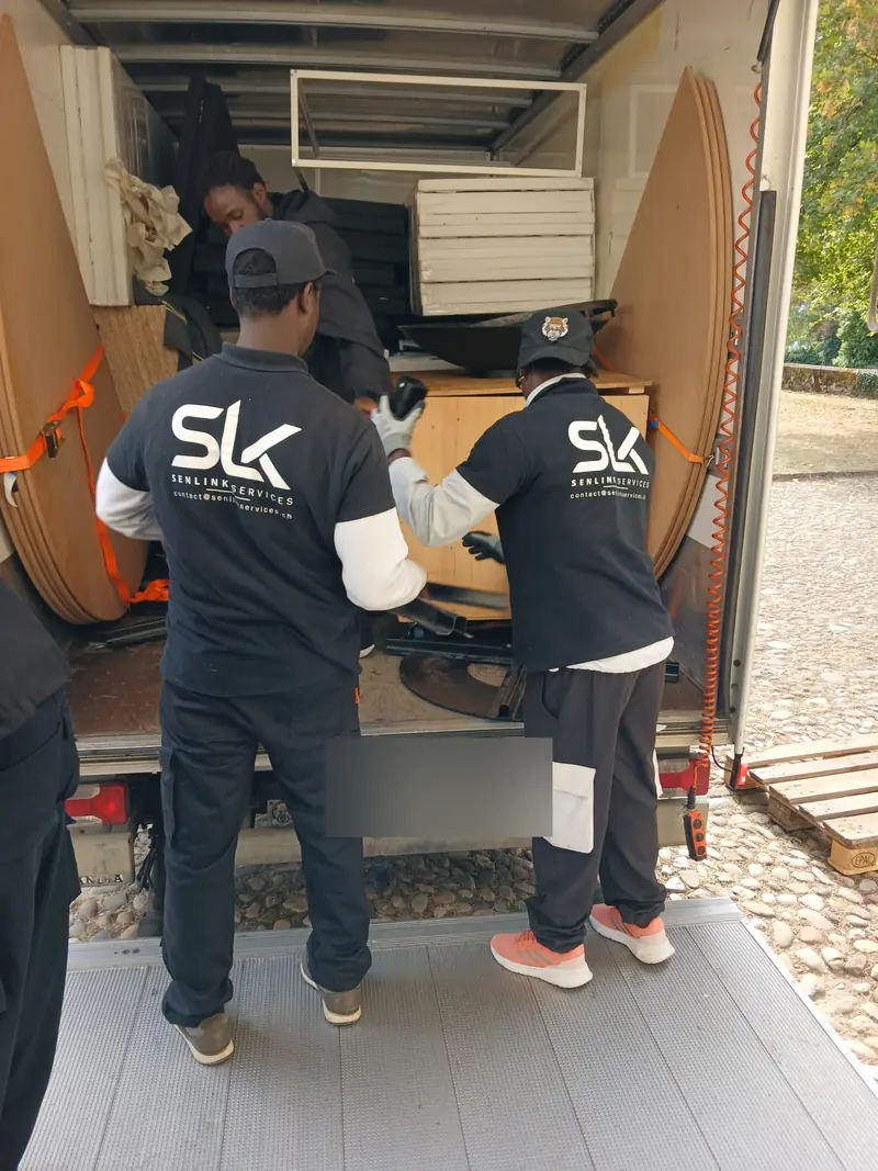 Drei Mitglieder des SENLINK-Teams beim Verladen von Möbeln in einen Lastwagen